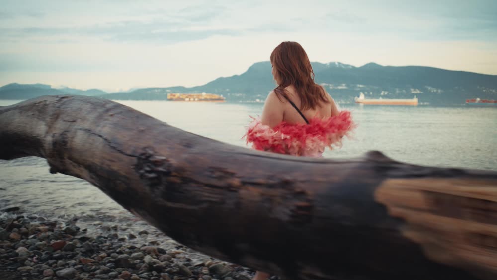 A woman on a beach log looking out over the water