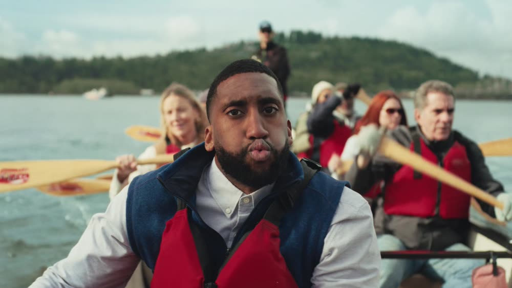 A paddler in a canoe with a crew behind him